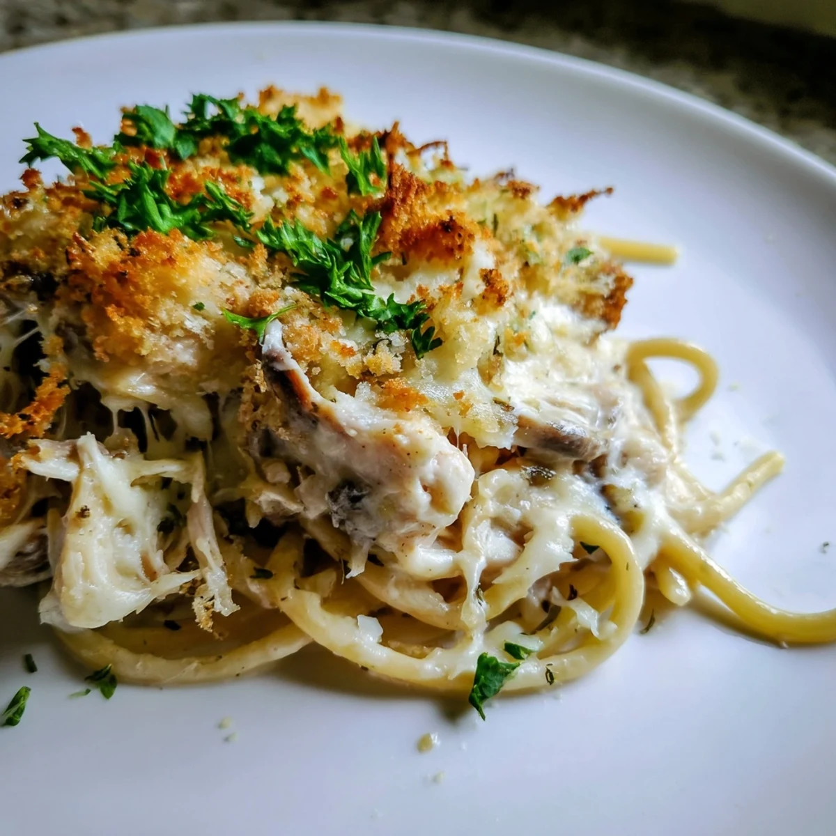 Golden-brown Turkey Tetrazzini with mushrooms, bubbling in the baking dish, ready to serve with a garnish.