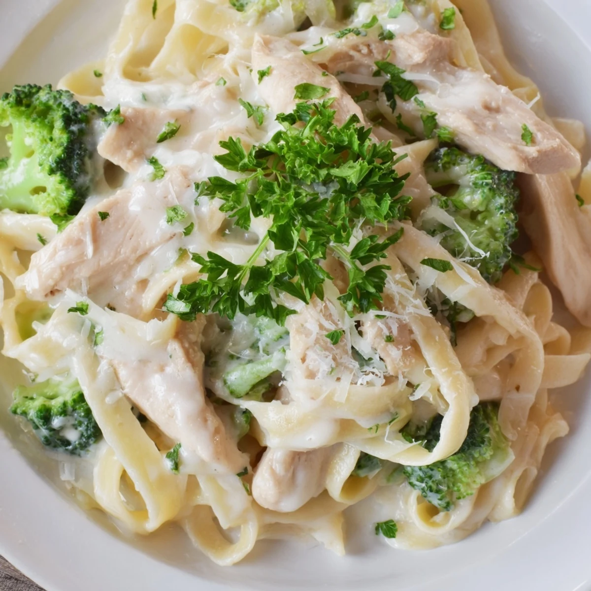 Steaming fettuccine pasta with tender chicken and broccoli florets coated in a rich homemade Alfredo sauce.