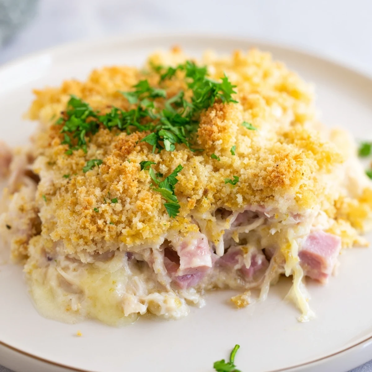 A spoonful of creamy Chicken Cordon Bleu Casserole reveals tender chicken, diced ham, and melted Swiss cheese in a rich sauce.