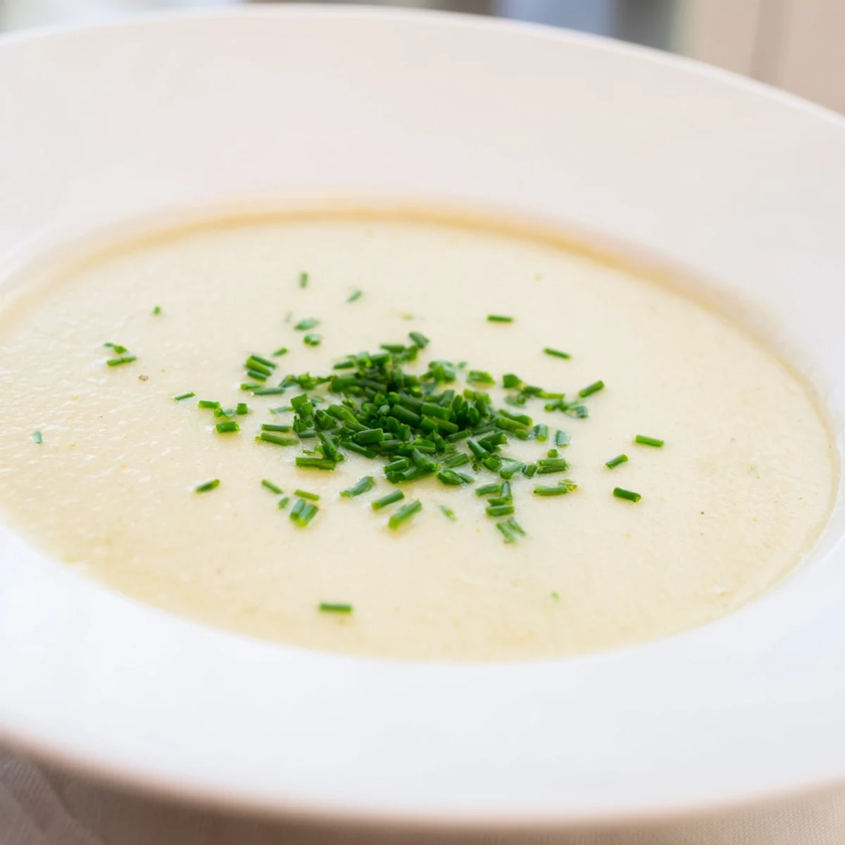 Silky smooth Creamy Leek Soup in a white ceramic bowl, garnished with parsley, showcasing a rich, comforting French-inspired meal.