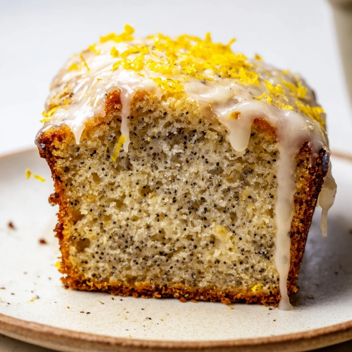 Golden slices of Lemon Poppy Seed Loaf with Lemon Glaze, drizzled and served on a rustic plate beside fresh berries.  