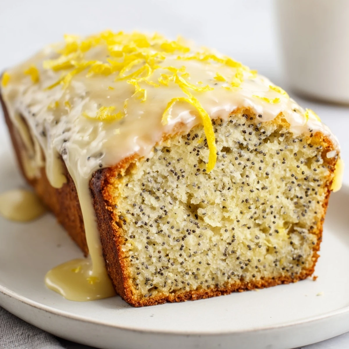 Freshly baked Lemon Poppy Seed Loaf with Lemon Glaze showing a moist crumb, glistening glaze, and visible poppy seeds.  