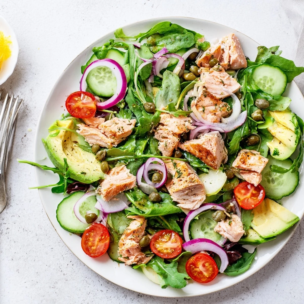 A wholesome lunch salad featuring tender baked salmon, avocado, and crisp veggies, finished with a zesty lemon dressing.
