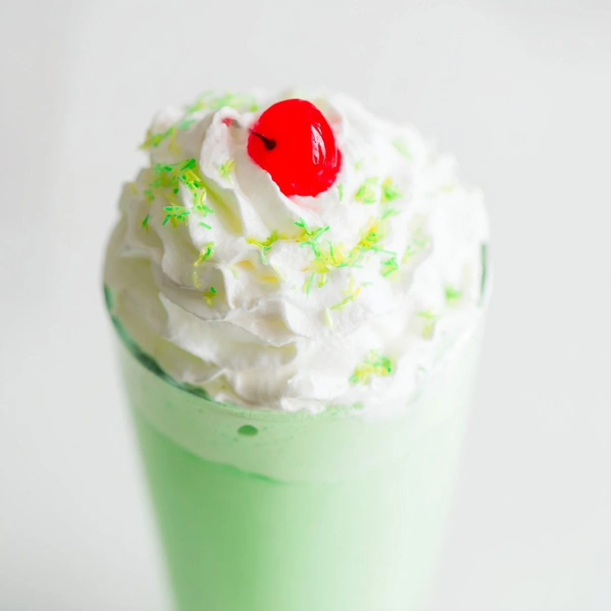 Tall glasses of Shamrock Mint Milkshake with a maraschino cherry and whipped cream