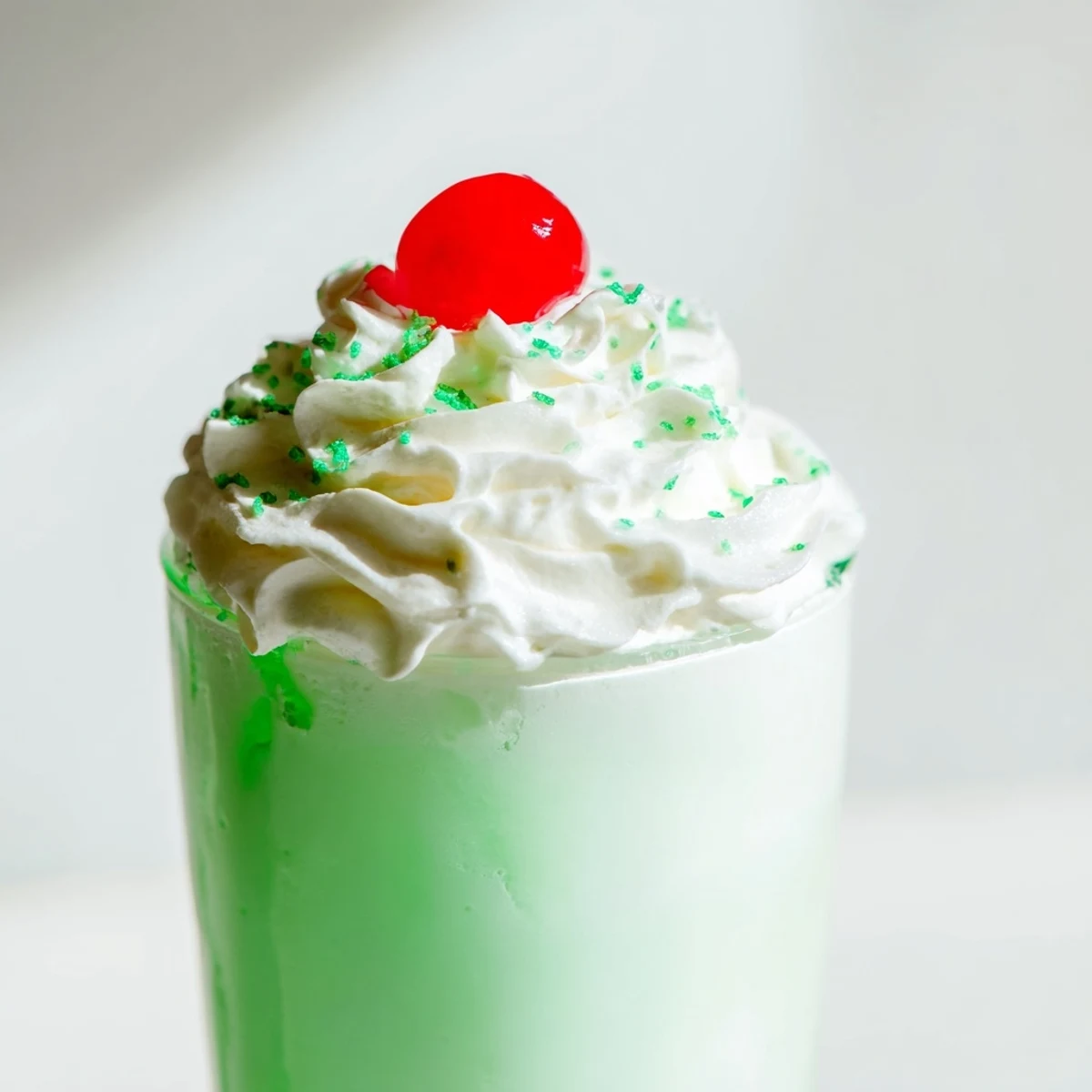 Thick, creamy Shamrock Mint Milkshake with green sprinkles and a bright cherry
