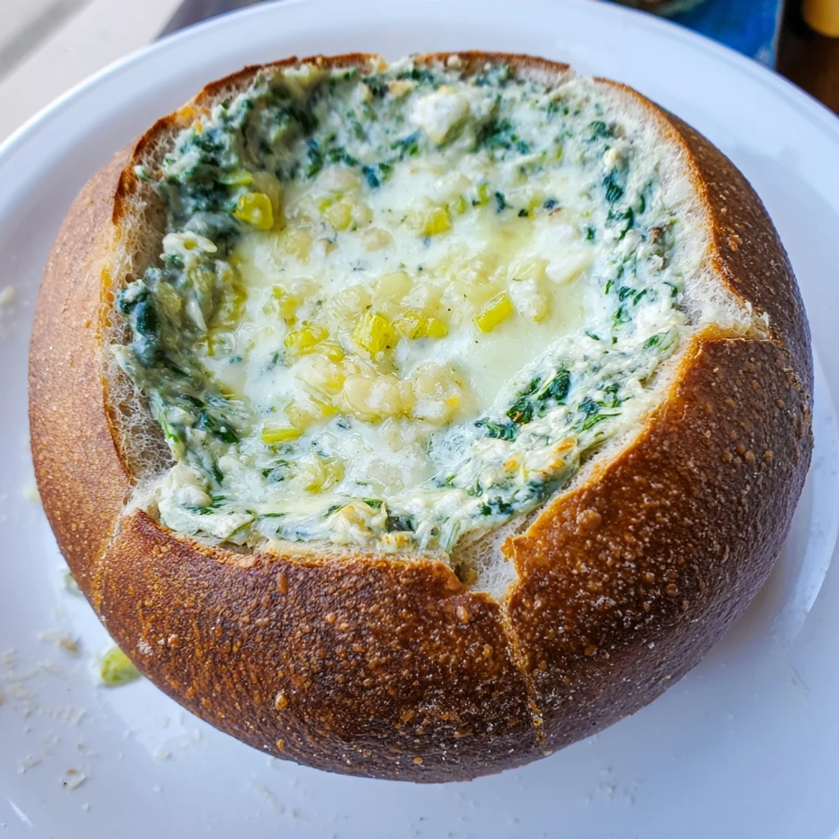 Steaming hot spinach dip spills from a hollowed-out sourdough bread bowl, a perfect Super Bowl appetizer.