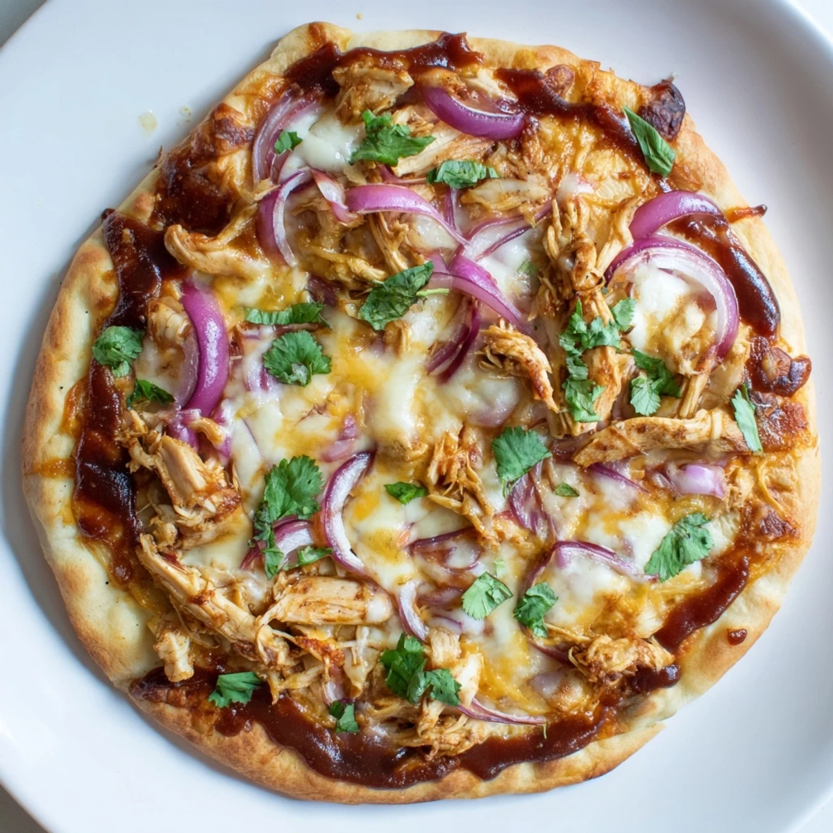 A close-up view of a warm slice of BBQ Chicken Pizza, highlighting the crispy, golden-brown crust edge and the sweet, tangy barbecue sauce base melding with gooey cheese.