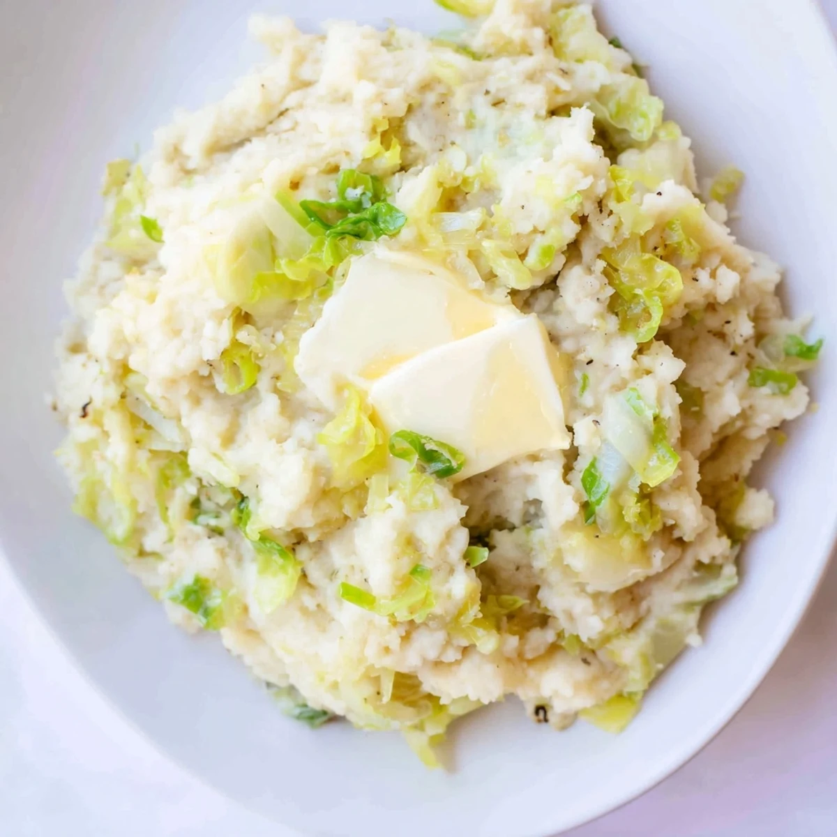 Golden Irish Colcannon Mashed Potatoes with Butter blended with cabbage and scallions, served beside corned beef for dinner.