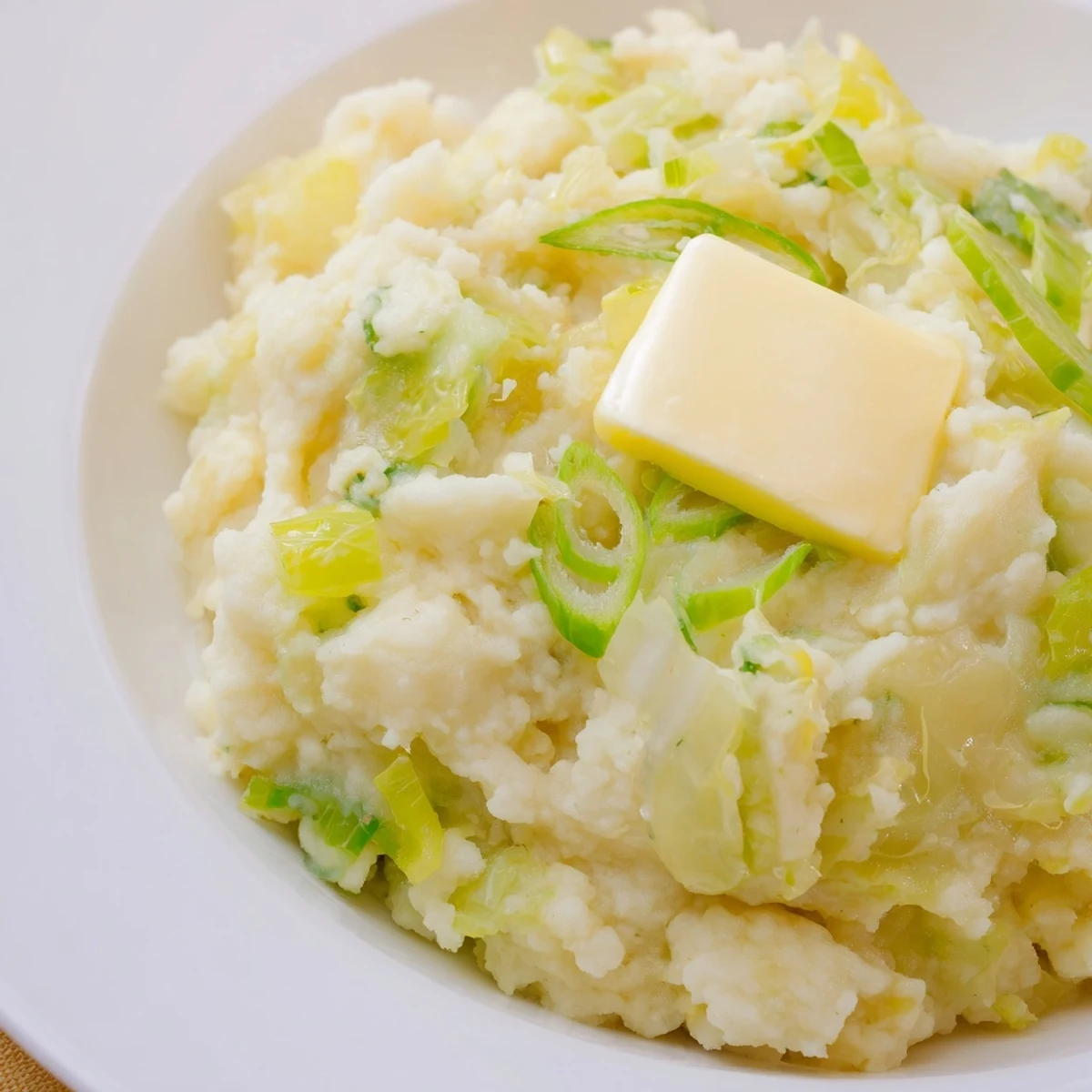 Rustic bowl of Irish Colcannon Mashed Potatoes with Butter mixed with tender cabbage and green onions, ready to eat.