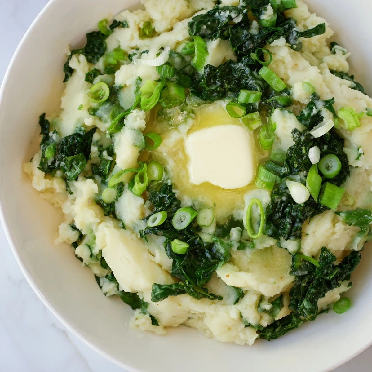 Creamy Irish Colcannon with kale and butter in a rustic bowl, garnished with extra melted butter.