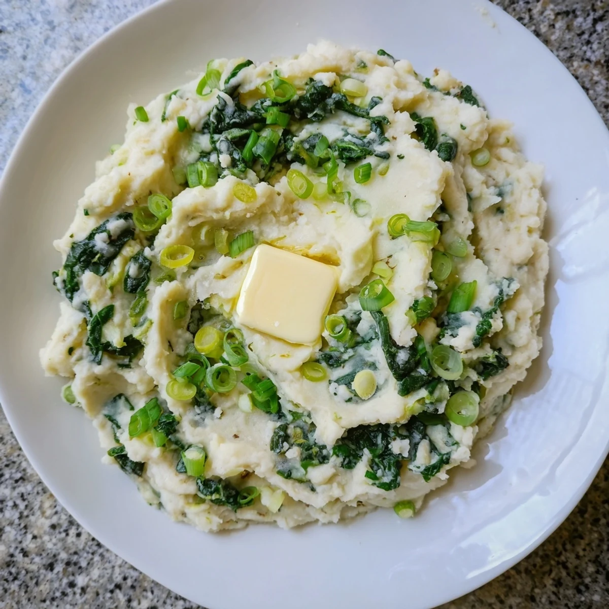 A close-up of Irish Colcannon with Kale and Butter showing creamy mashed potatoes flecked with green kale and a melting pat of butter.