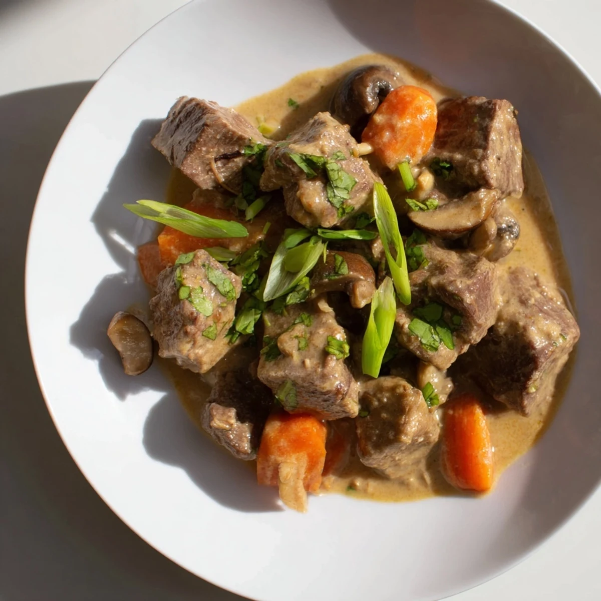 Steaming pot of Lemongrass Coconut Braised Beef with Mushrooms, garnished with cilantro and lime.