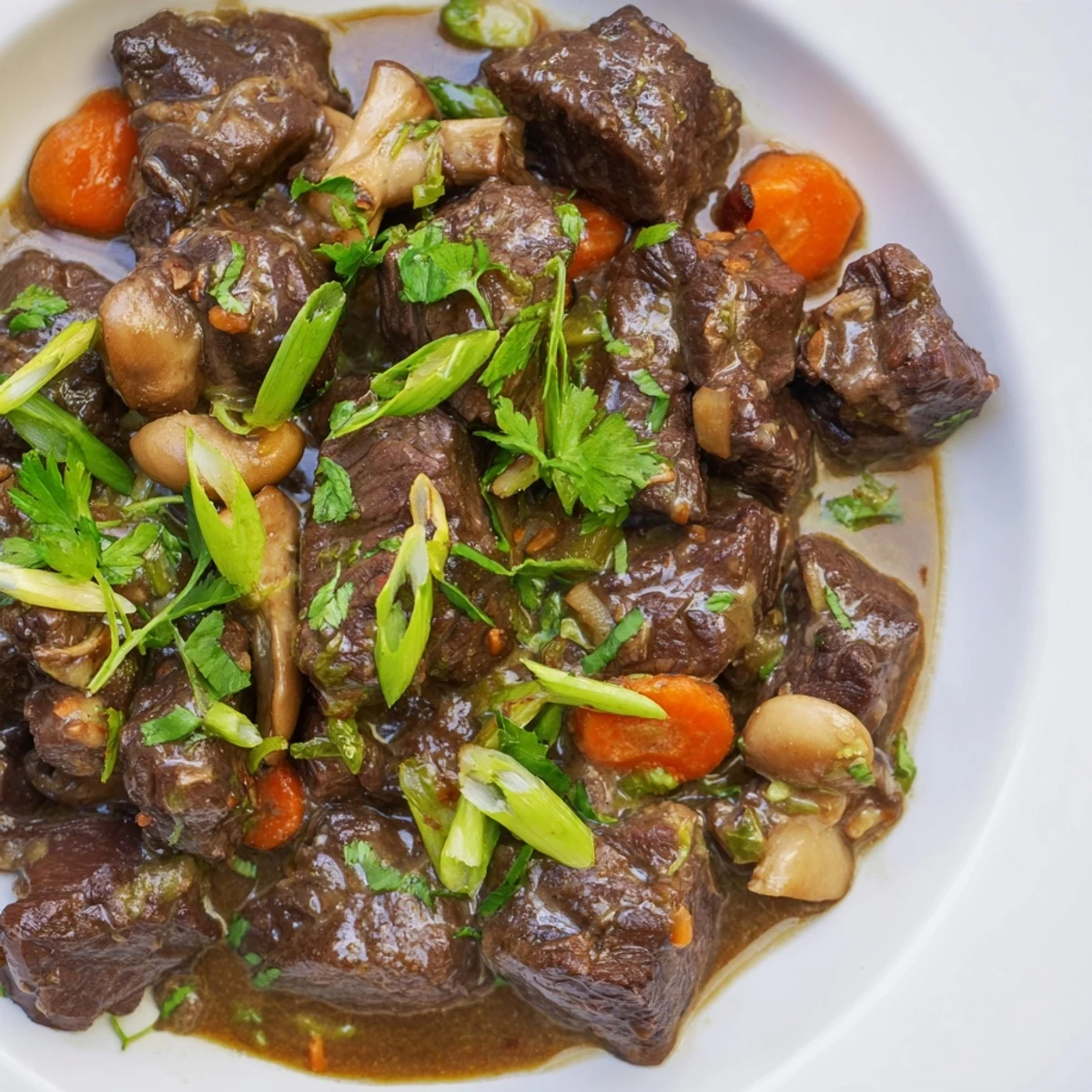 Close-up of tender Lemongrass Coconut Braised Beef with Mushrooms on a plate next to rice.