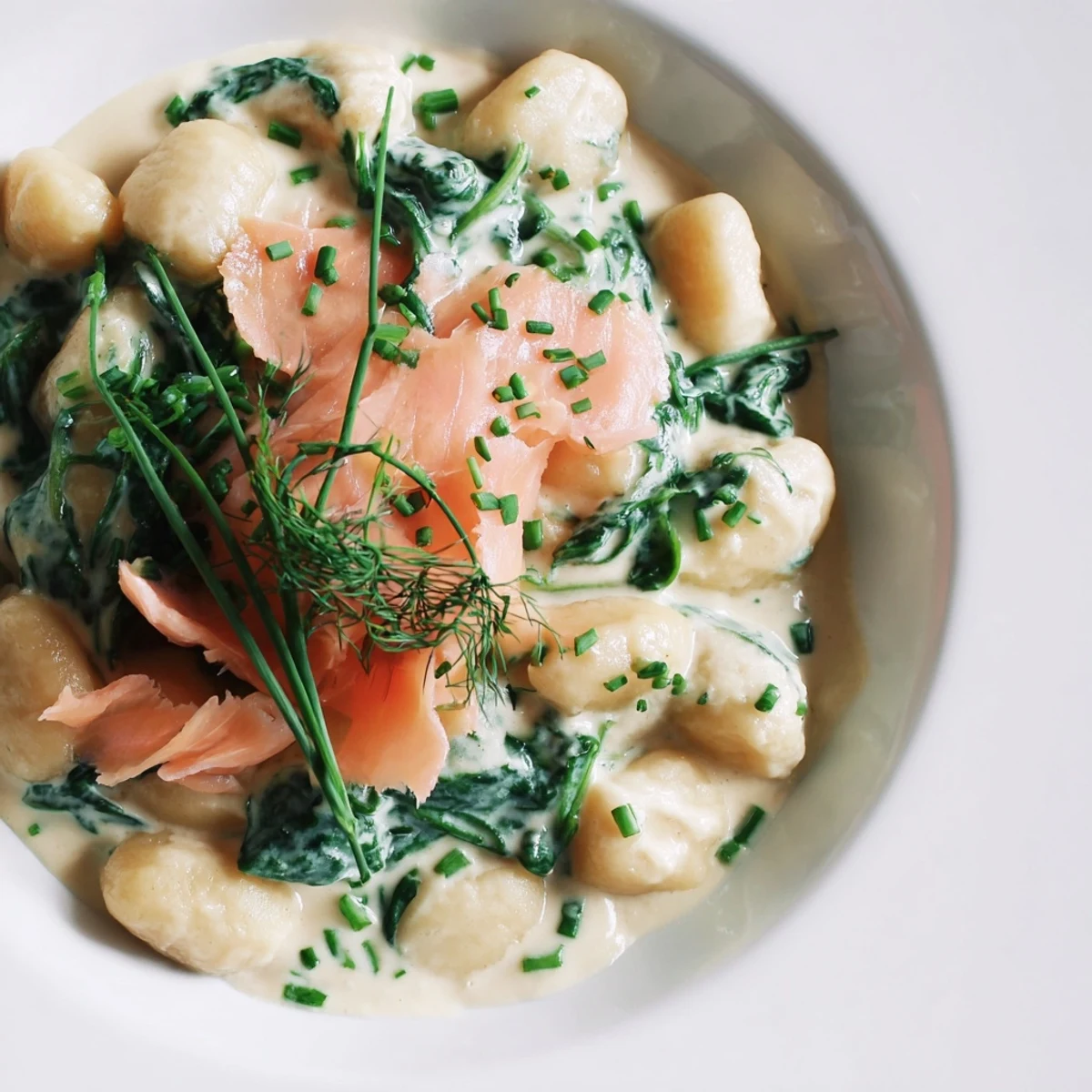 A close-up of Healthy Smoked Salmon Gnocchi with lemon wedges, spinach, and silky salmon strips ready for a weeknight meal.