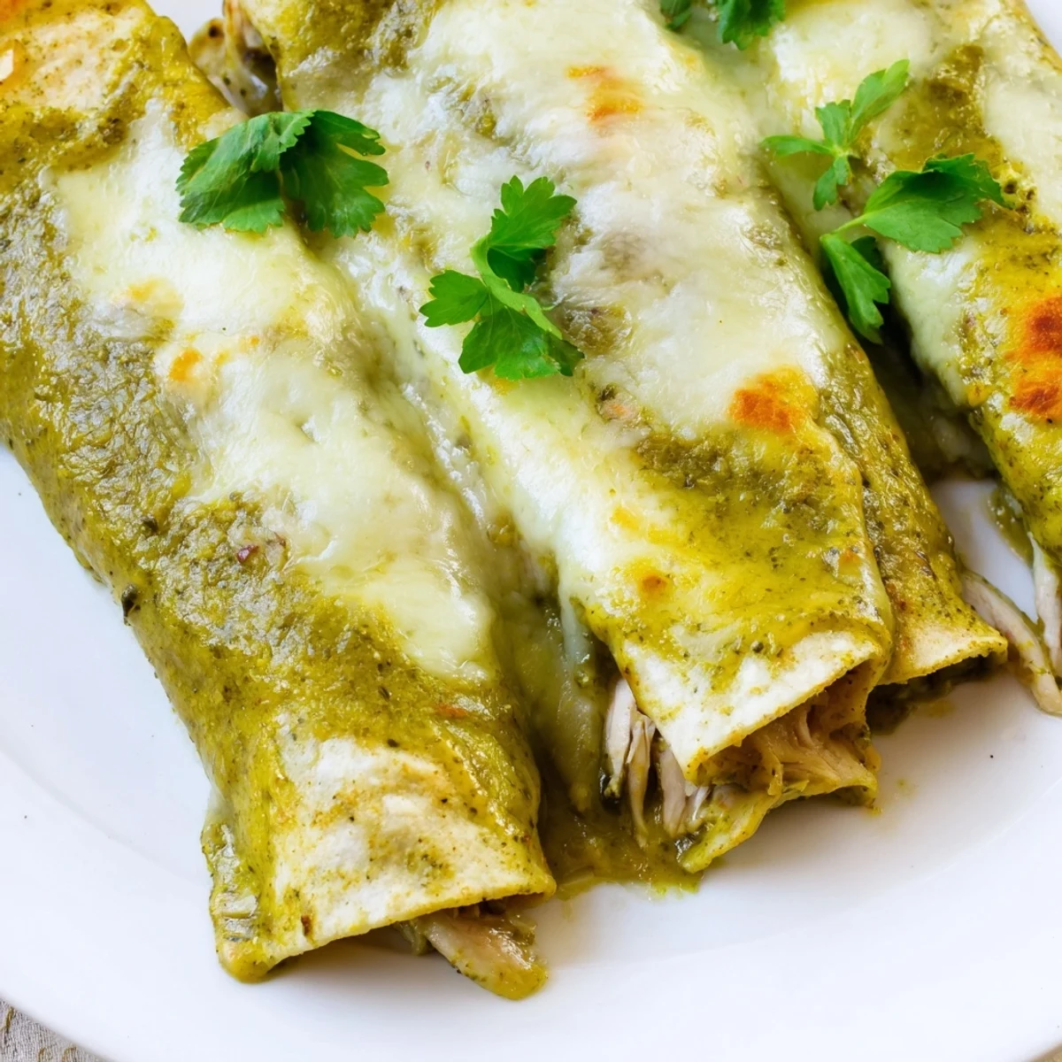 Freshly baked Green Enchiladas With Chicken steaming beside a lime wedge, ready for a delicious Mexican-inspired dinner.