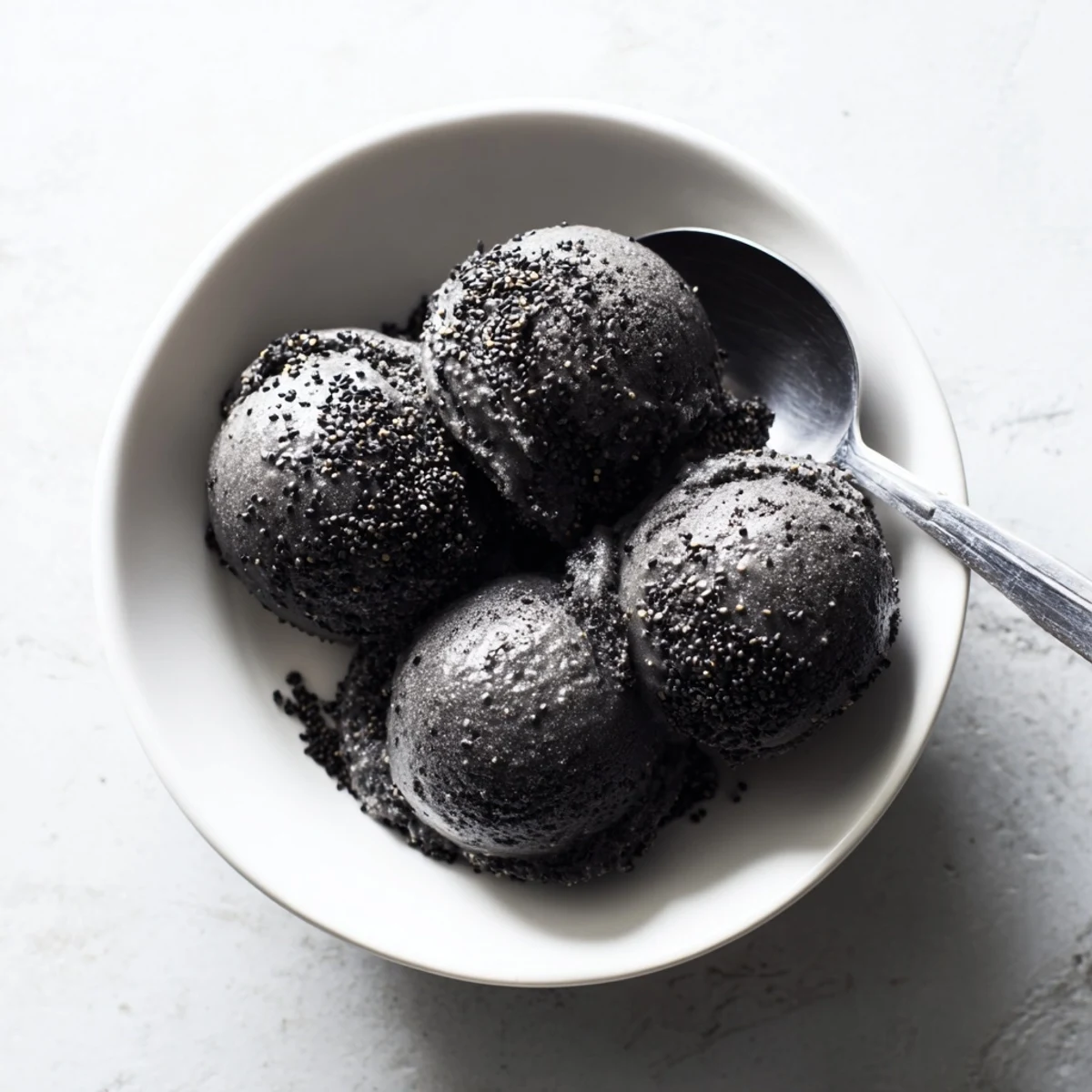 Creamy Toasted Black Sesame Ice Cream scoops into a rich, nutty frozen dessert served in a chilled bowl.