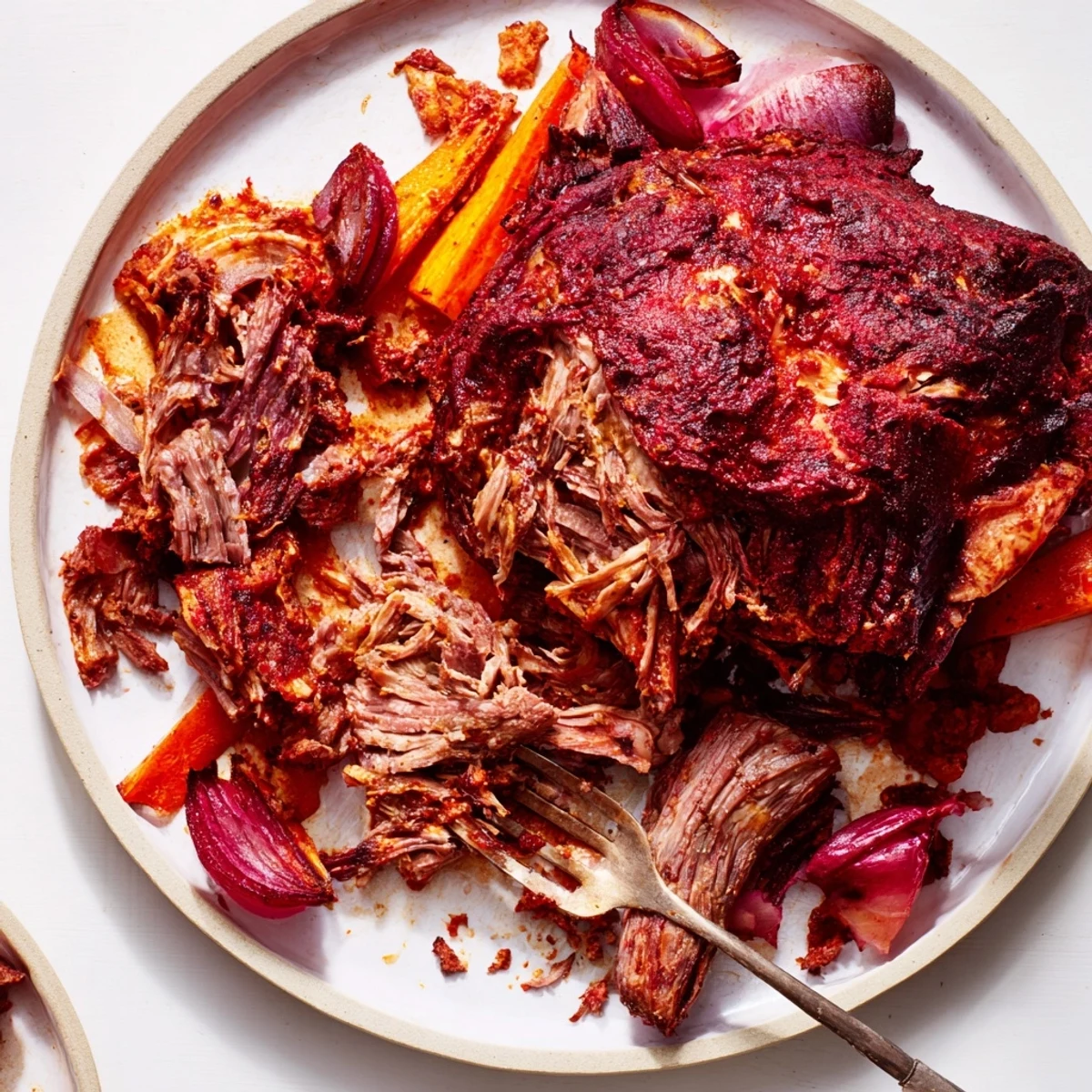 The Slow Roasted Harissa Lamb Shoulder rests on a bed of caramelized onions and carrots, filling the air with a smoky, aromatic scent.