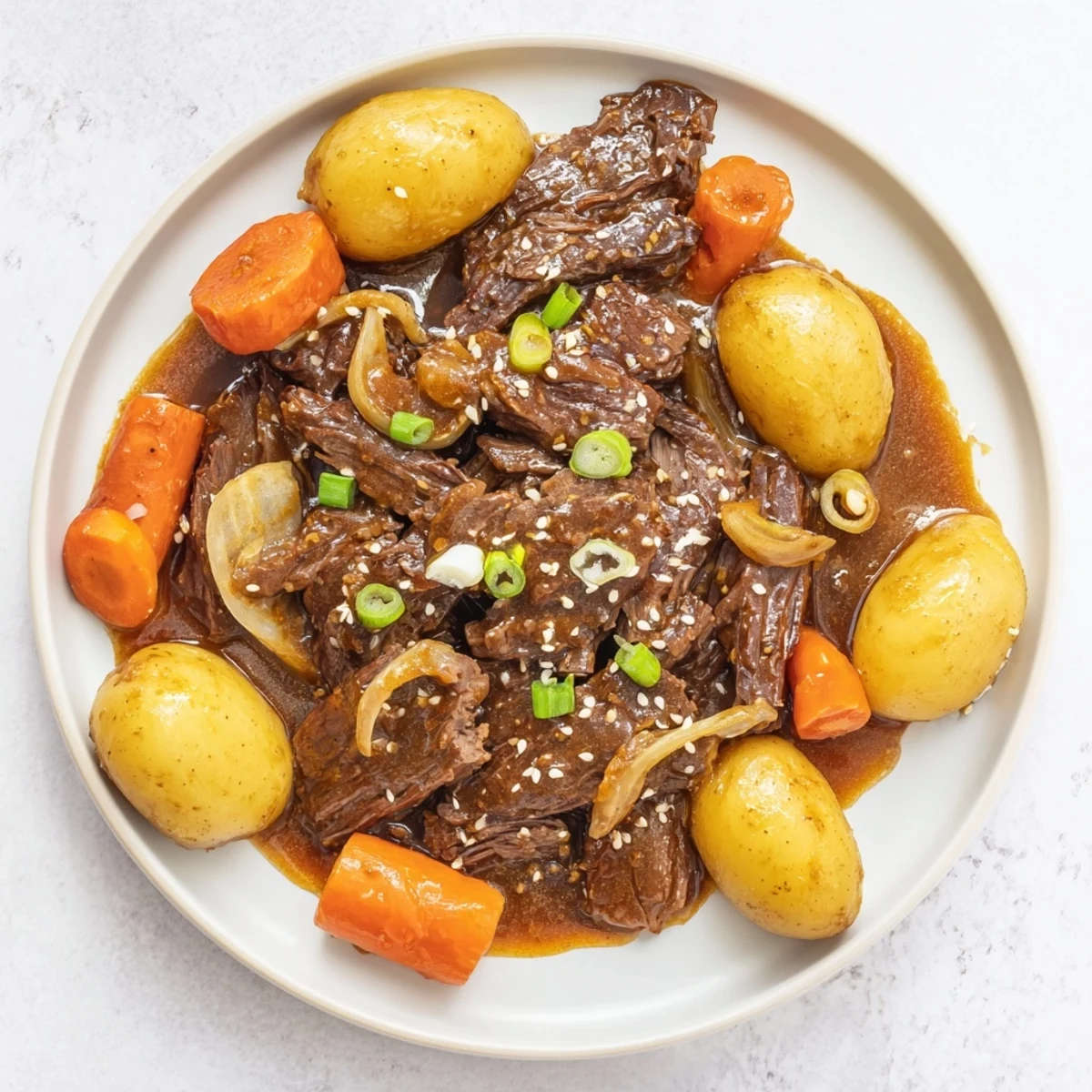 Slow cooker Korean beef pot roast with tender shredded beef and rich soy garlic gravy over carrots and potatoes.