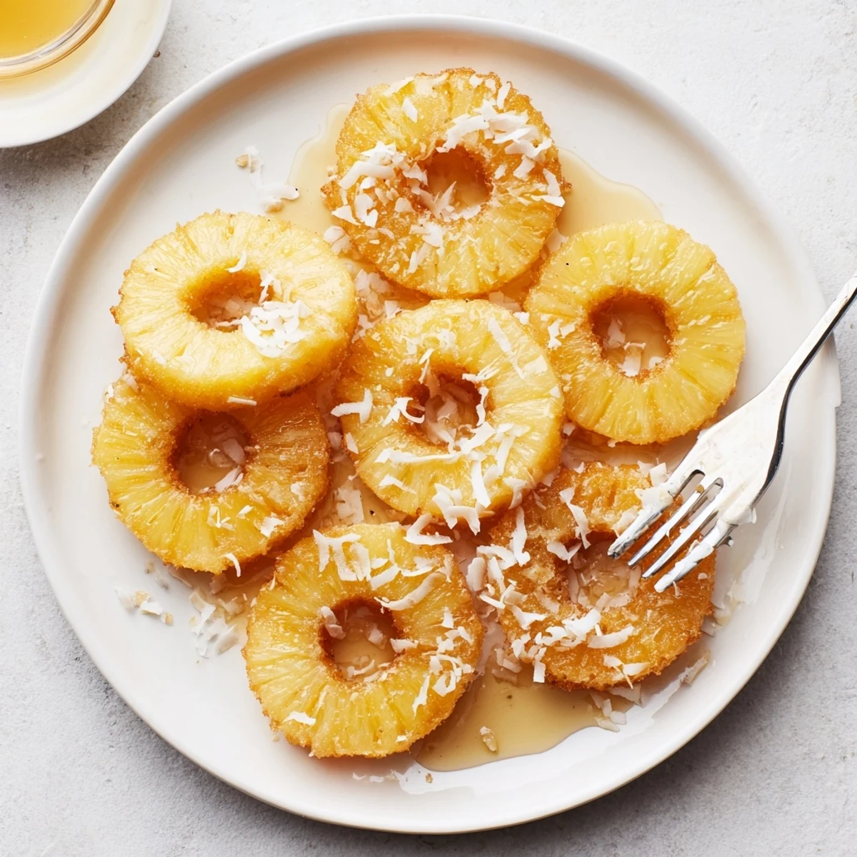 Fried Pineapple served warm on a plate with a drizzle of syrup, showcasing its juicy interior and crunchy, golden exterior.