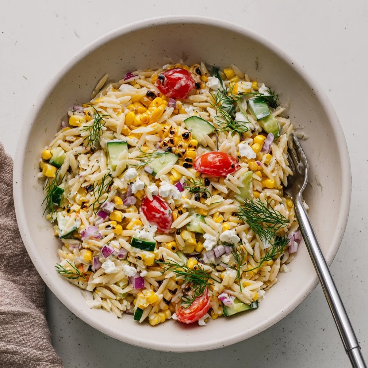 Golden grilled corn kernels mingle with tender orzo, diced cucumber, and cherry tomatoes in this refreshing salad.
