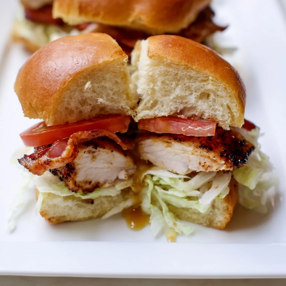 The finished Honey Mustard BLT Chicken Sliders on a platter, showing juicy sliced chicken, crispy bacon, fresh lettuce, and ripe tomato on toasted slider buns with a drizzle of sauce.