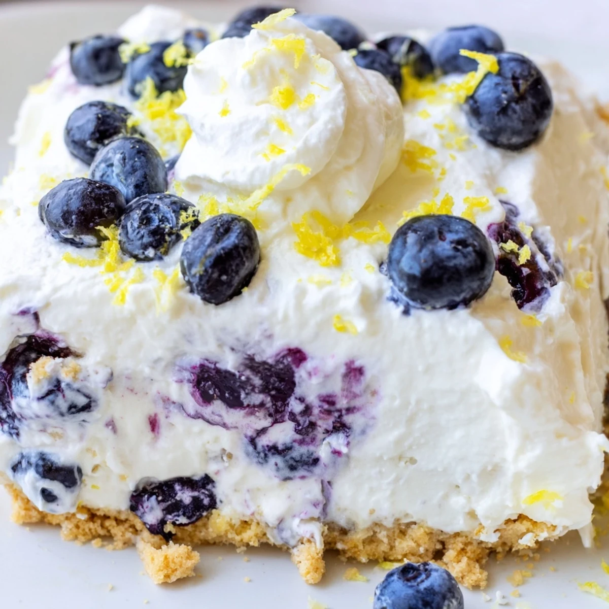 Golden graham cracker crust supports creamy no bake lemon blueberry cream cake topped with fresh blueberries