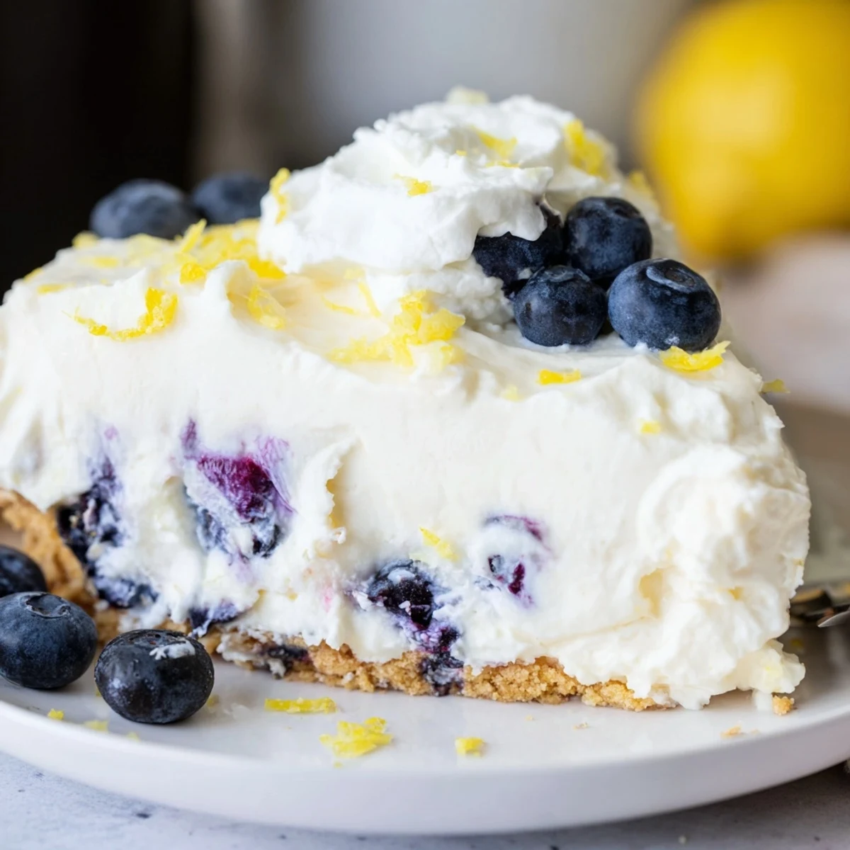 Summer dessert featuring no bake lemon blueberry cream cake with whipped cream and scattered fresh berries