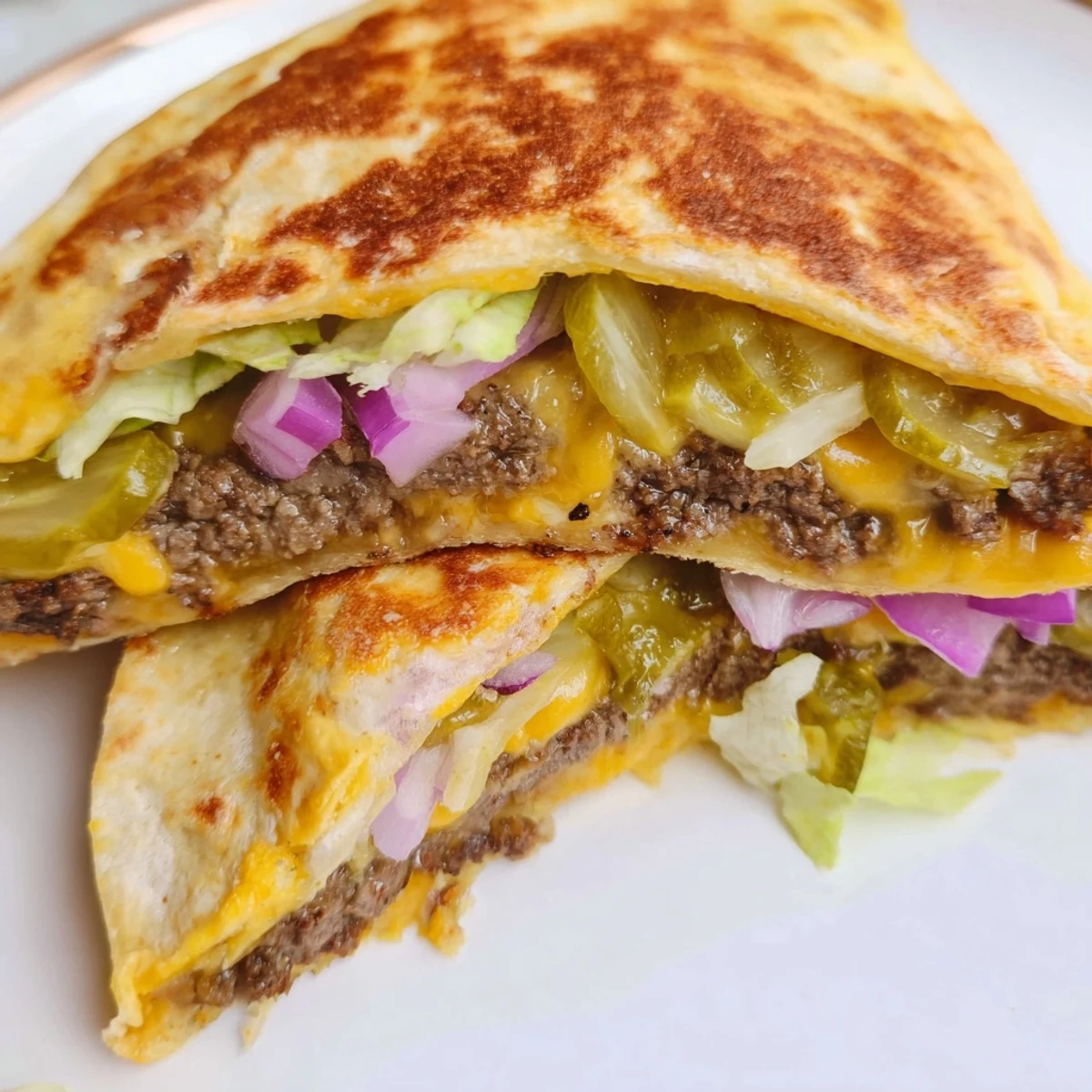 Golden smashburger quesadilla sliced open revealing melted cheddar, juicy beef patty, and crisp lettuce