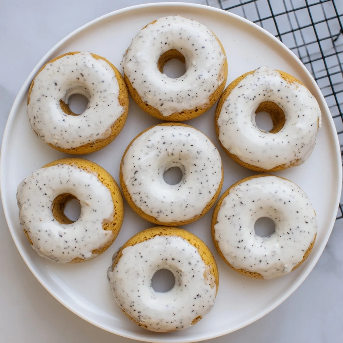 Freshly baked mochi donuts arranged on white plate with glossy Earl Grey glaze dripping