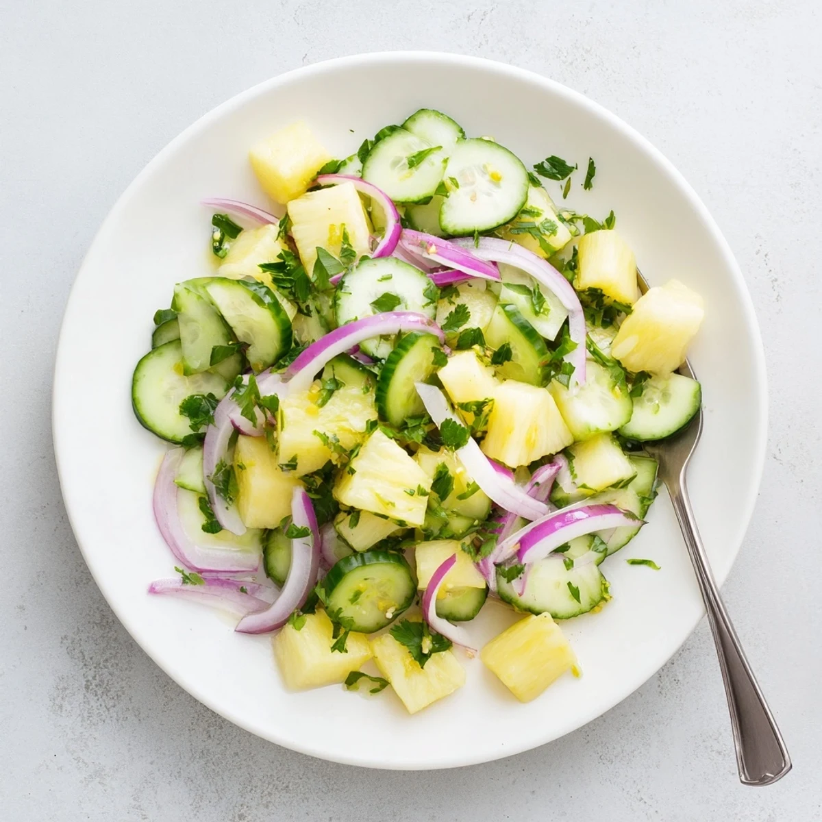Refreshing summer pineapple cucumber salad plated with red onion and zesty vinaigrette dressing