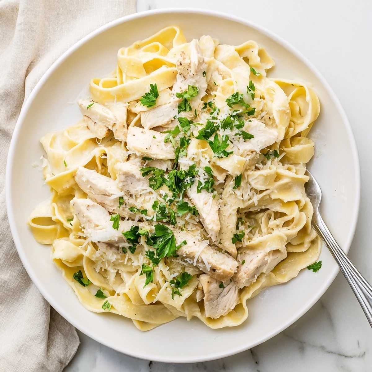 Golden sliced chicken rests over fettuccine pasta swimming in a velvety garlic Alfredo sauce