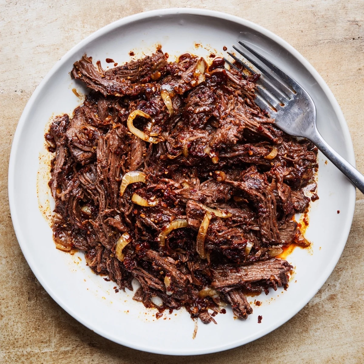 Savory slow cooker shredded beef piled high with aromatic onions and visible seasoning
