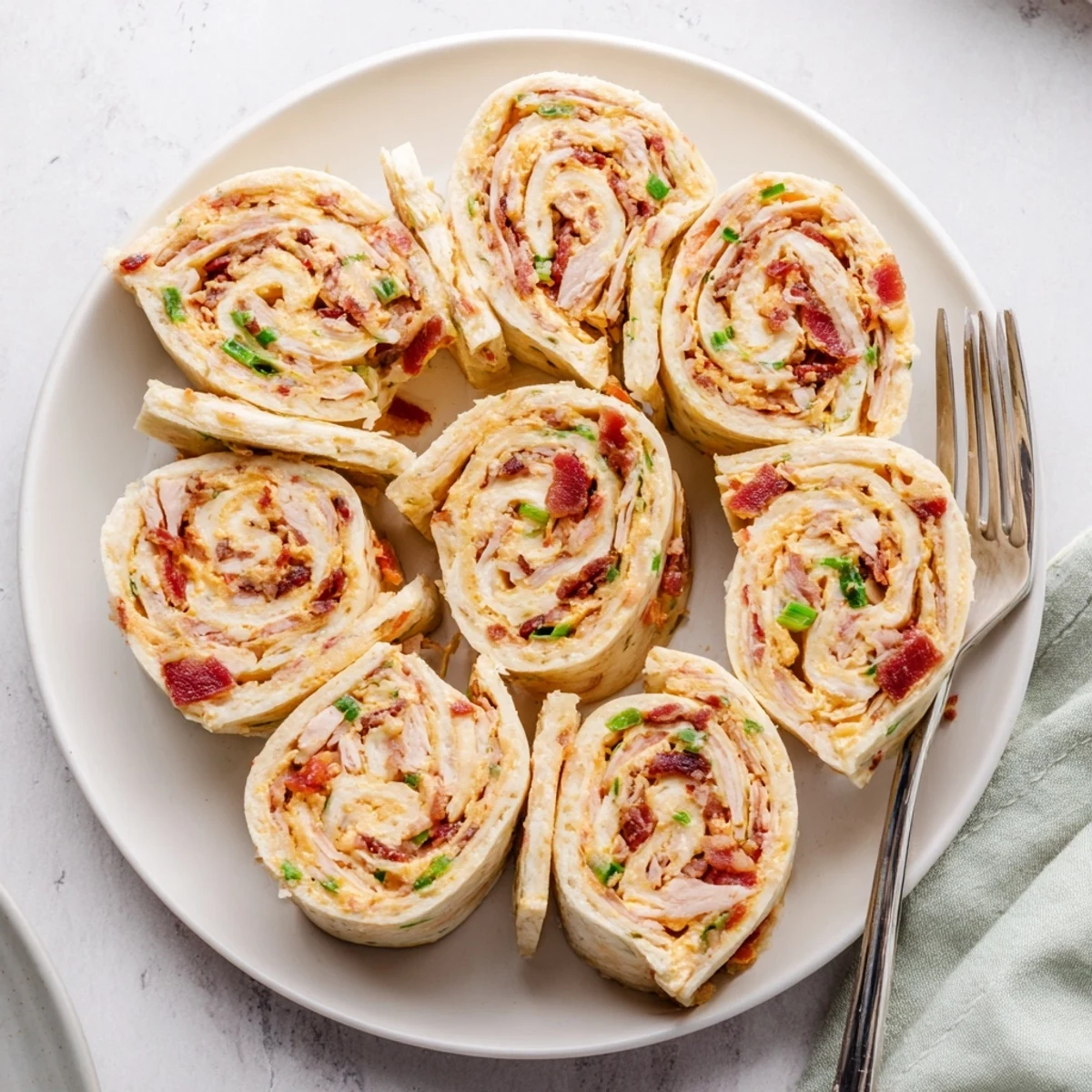 Sliced tortilla roll-ups filled with savory chicken and bacon mixture arranged neatly for party appetizer serving