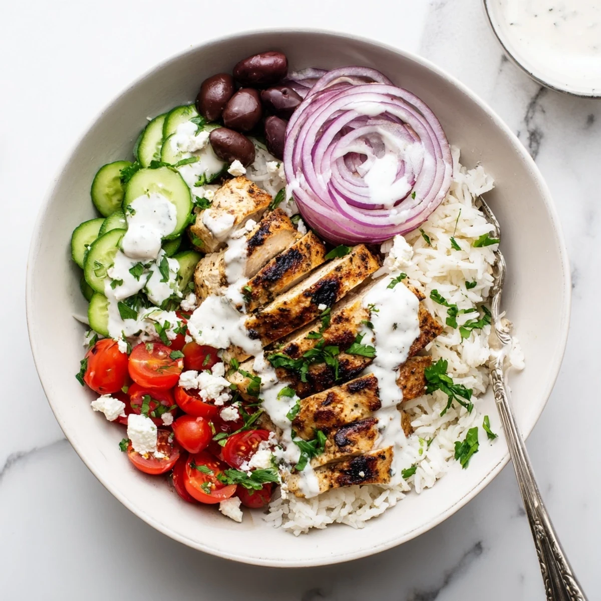 Golden sliced chicken atop fluffy rice with colorful Mediterranean vegetables and tangy yogurt sauce drizzled over Greek chicken bowls