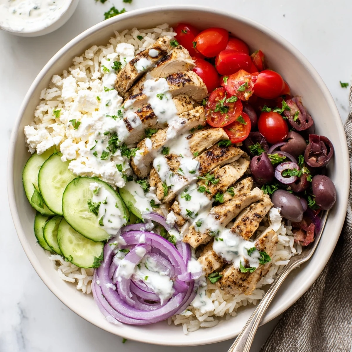 Vibrant meal prep bowl featuring tender spiced chicken over steaming rice topped with crunchy vegetables and herbed yogurt sauce in Greek chicken bowls