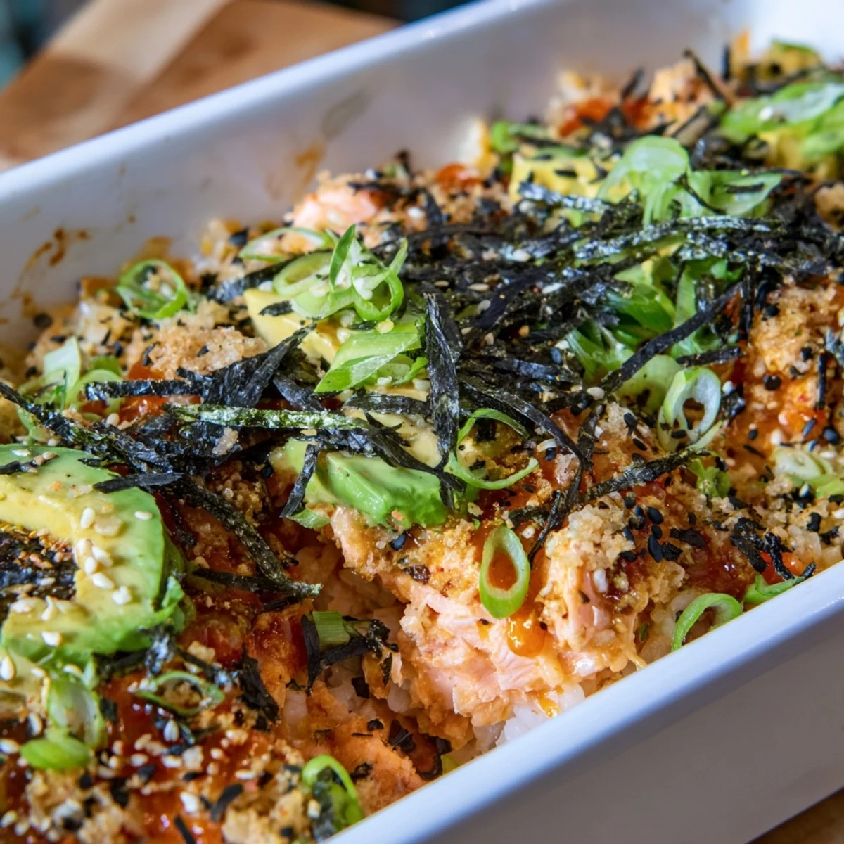 Golden baked salmon sushi bake casserole topped with creamy spicy mayo and fresh avocado slices