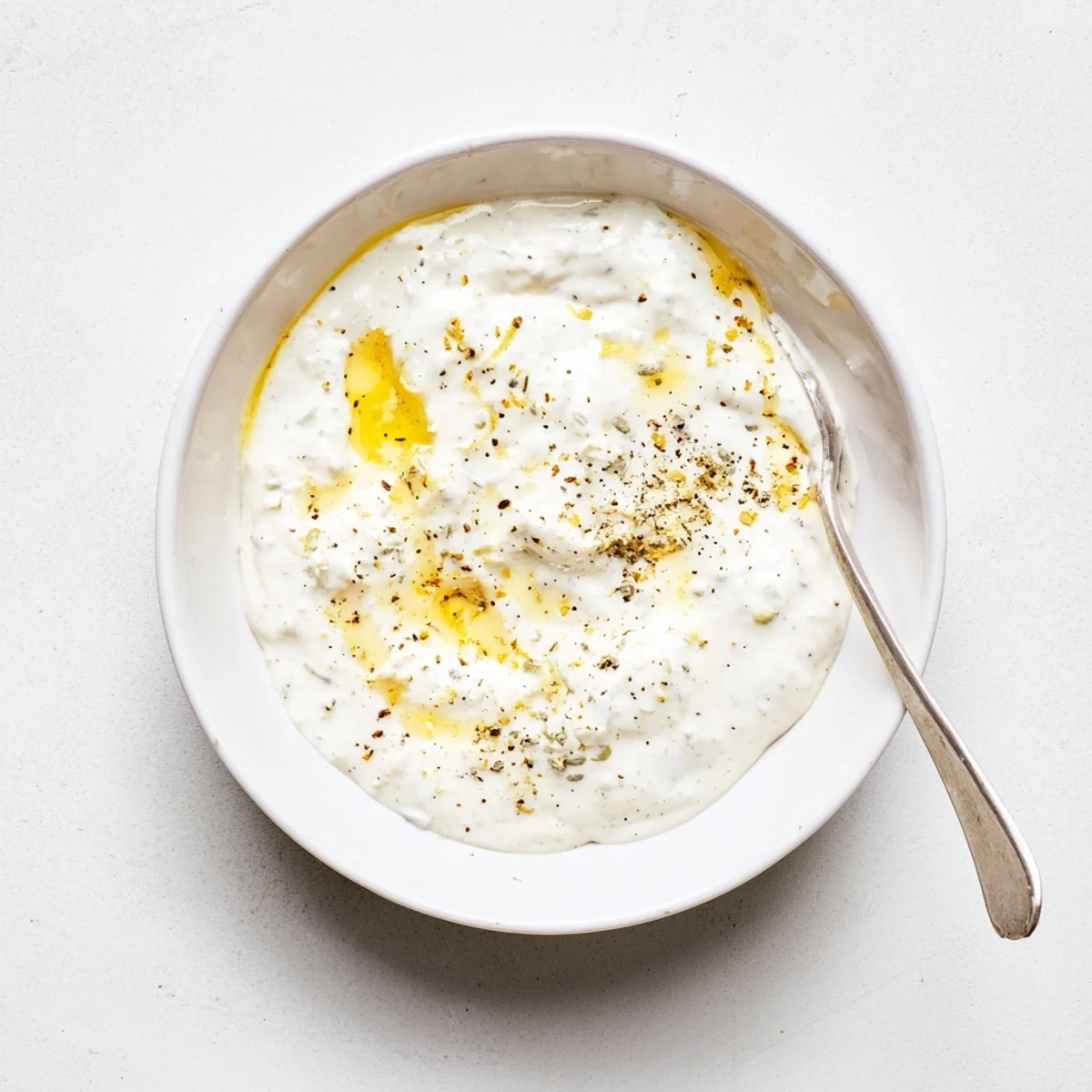 Rich garlic sauce for chicken shawarma displayed in a small white ramecken with fresh herbs sprinkled on top