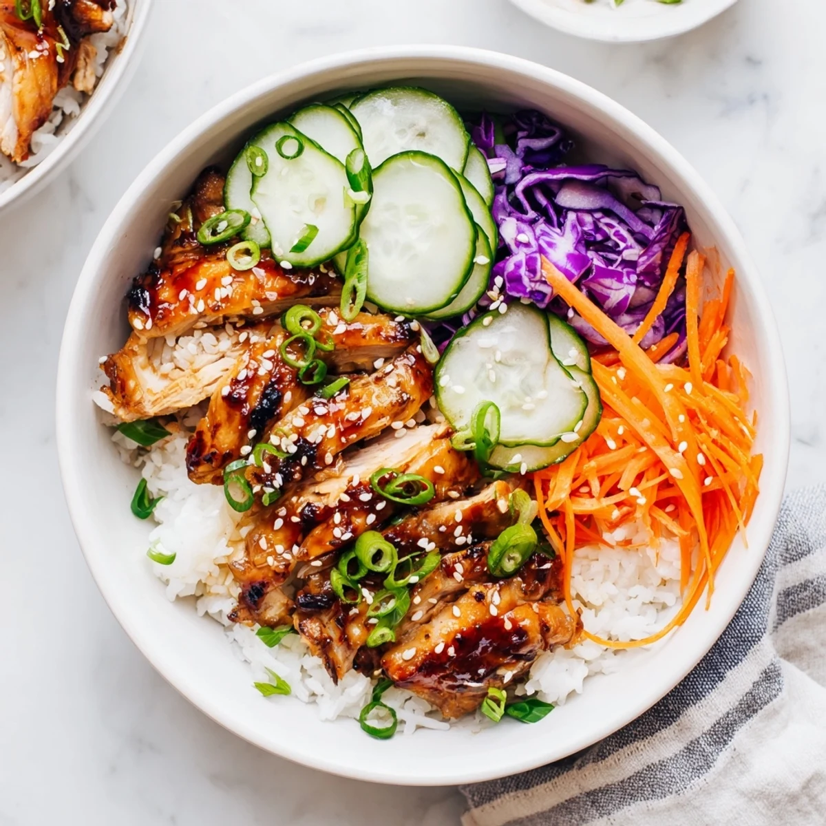 Savory Korean BBQ chicken bowl with marinated thighs sliced over rainbow vegetable rice bowl
