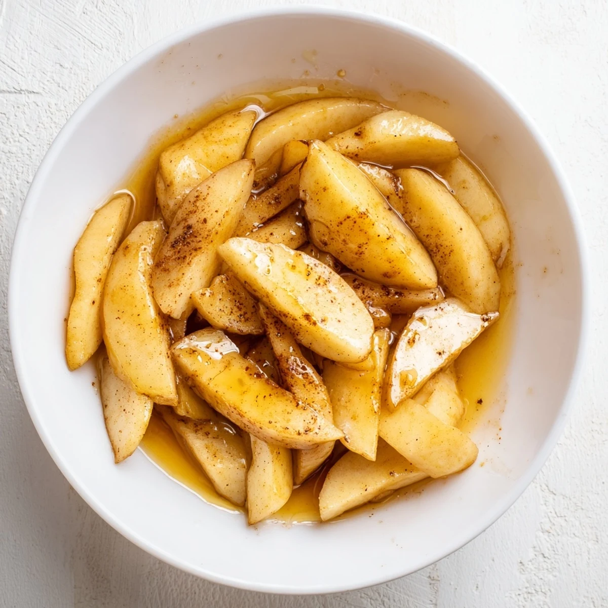 Tender cinnamon-spiced apples arranged in a bowl with a rich buttery glaze