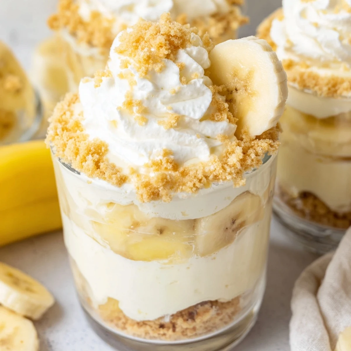 Individual no bake banana pudding cheesecake cups featuring luscious layers of cheesecake filling and banana pudding