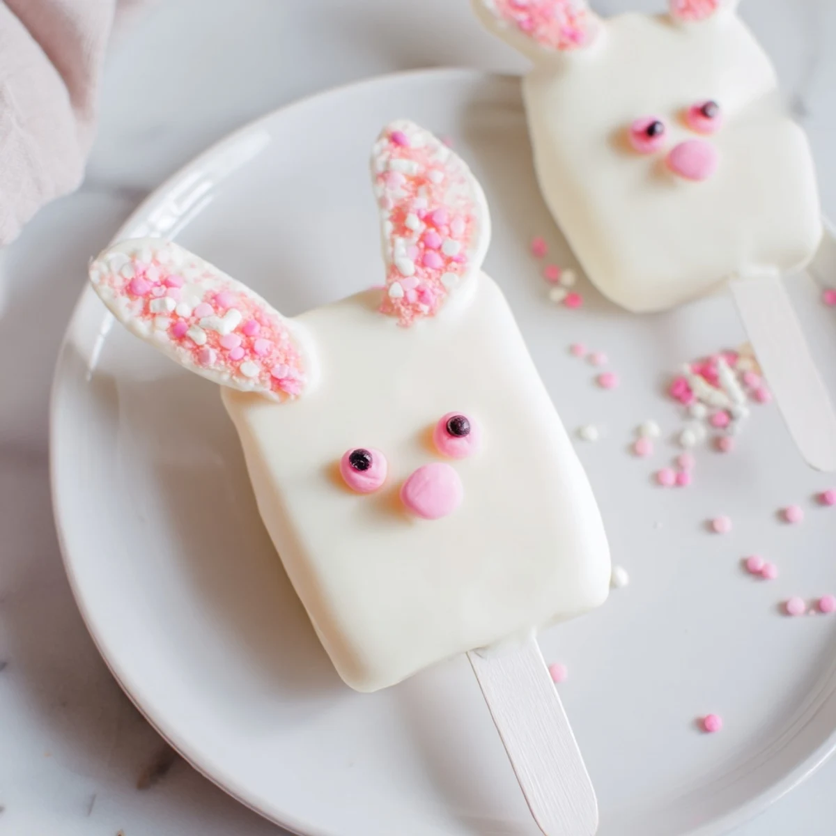 Adorable white chocolate bunny cakesicles with candy eyes and pink ears on sticks