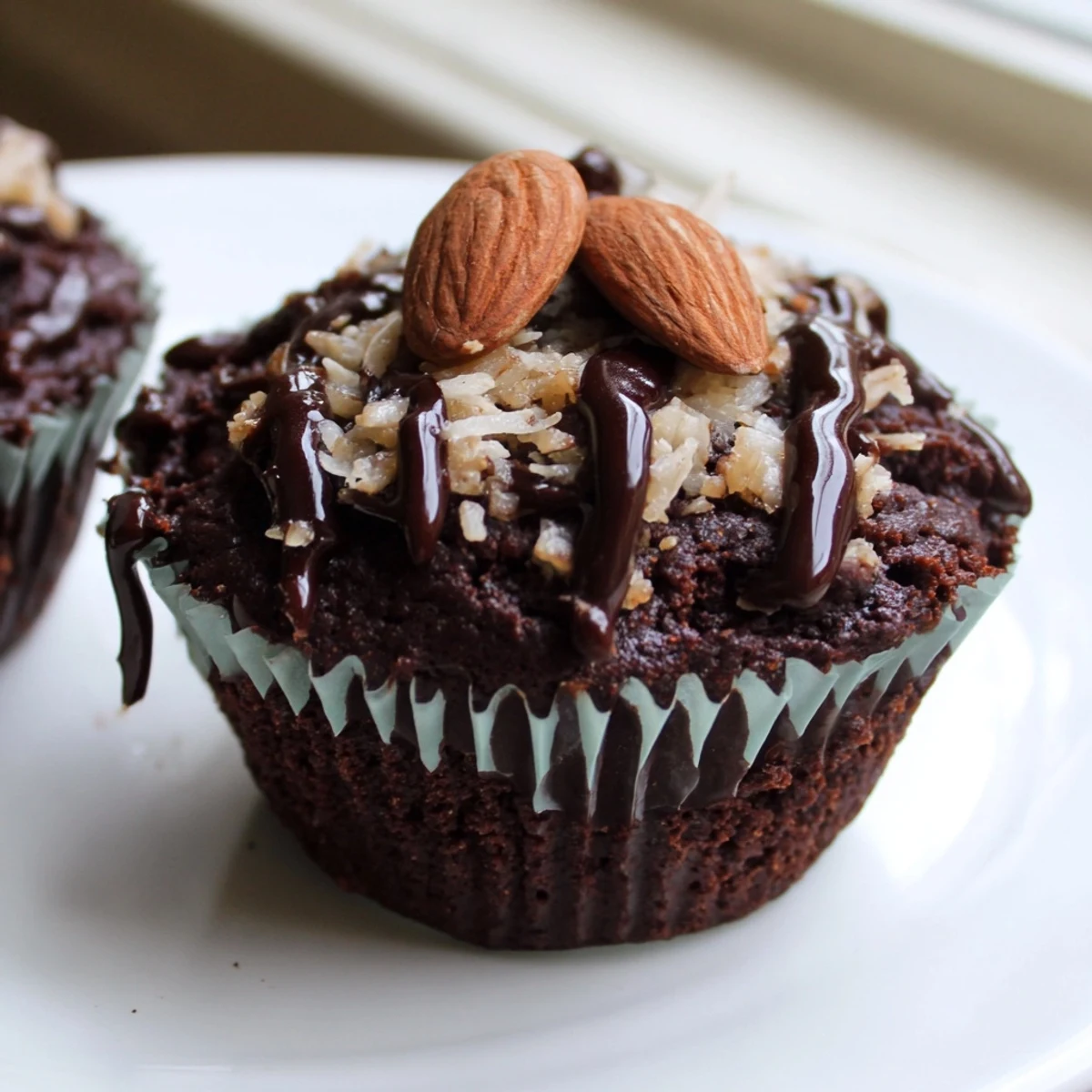 Fudgy Flourless Almond Joy Cupcakes garnished with toasted almonds and shredded coconut in a bakery-style display