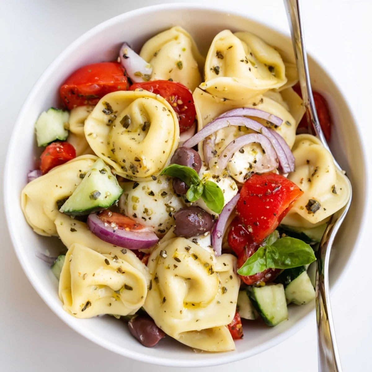 Tortellini Pasta Salad with vibrant cherry tomatoes and fragrant basil, chilled.