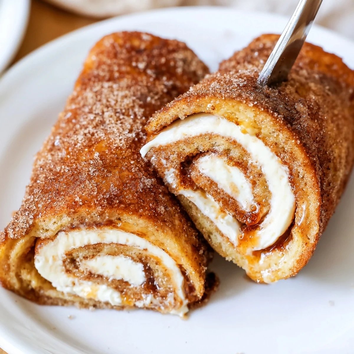 Cinnamon Roll French Toast Roll Ups frying in butter, powdered sugar dusted