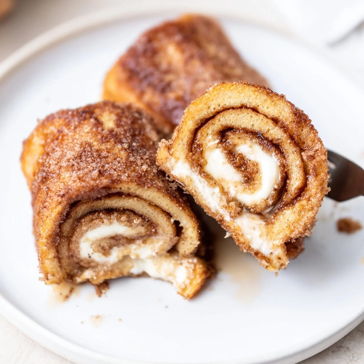 Cinnamon Roll French Toast Roll Ups rolled tight, creamy center, served with maple syrup  
