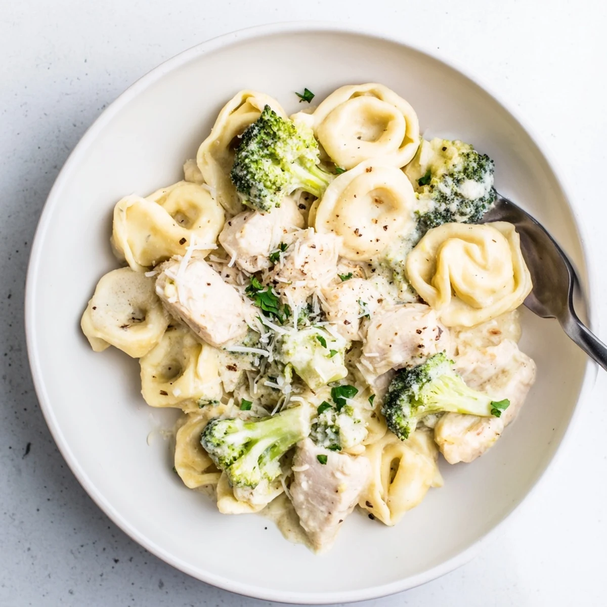Warm Creamy Garlic Parmesan Tortellini Chicken Broccoli Recipe in shallow bowl, tender bites