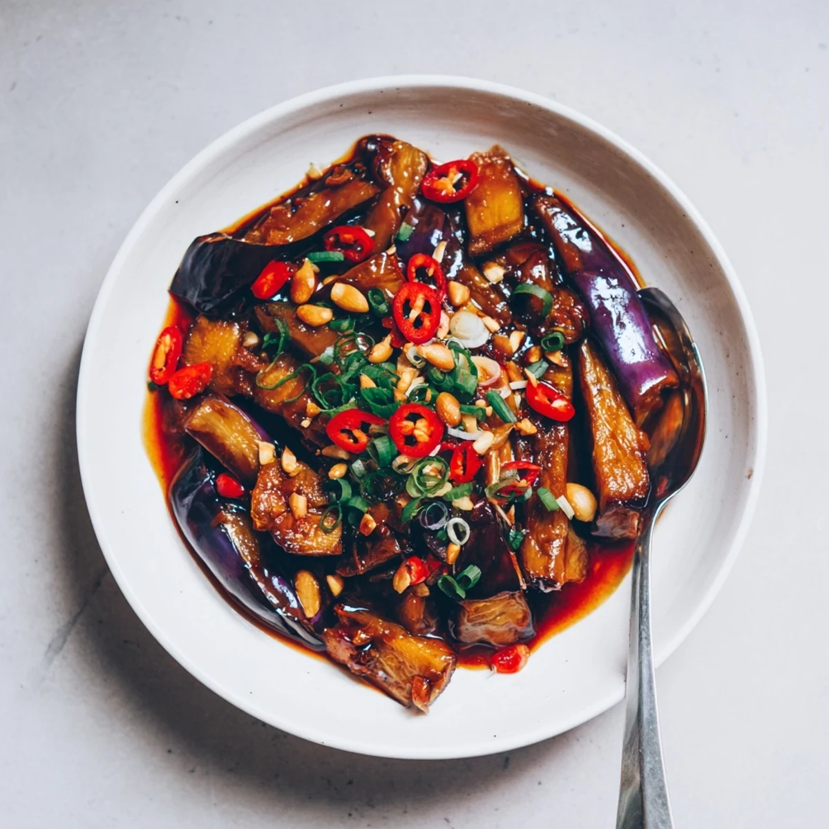 Sichuan Style Braised Aubergines glistening in spicy red sauce, scallions atop