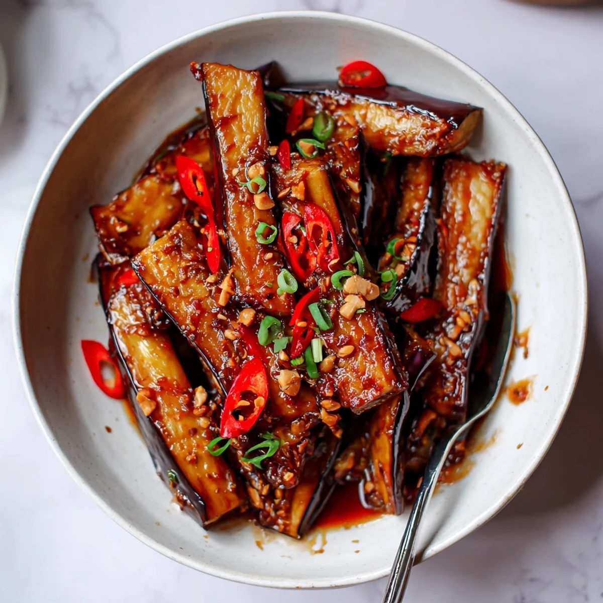 Aromatic Sichuan Style Braised Aubergines served over steamed jasmine rice, sliced chili