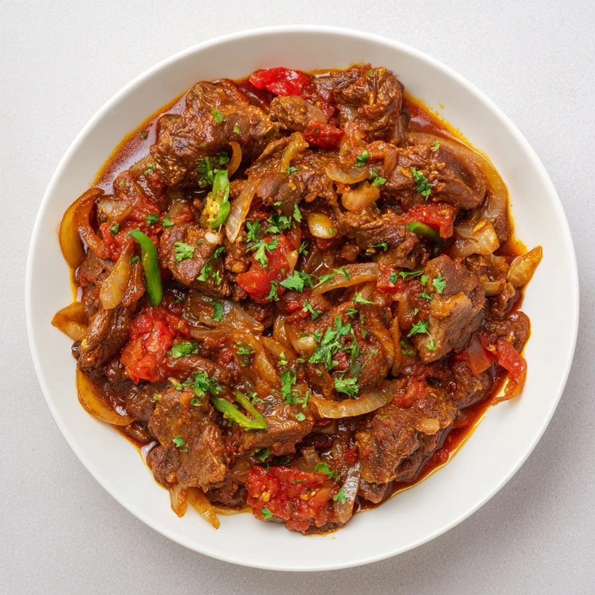 Delicious Kenyan goat wet fry served hot with tender chunks swimming in spiced tomato and onion gravy.