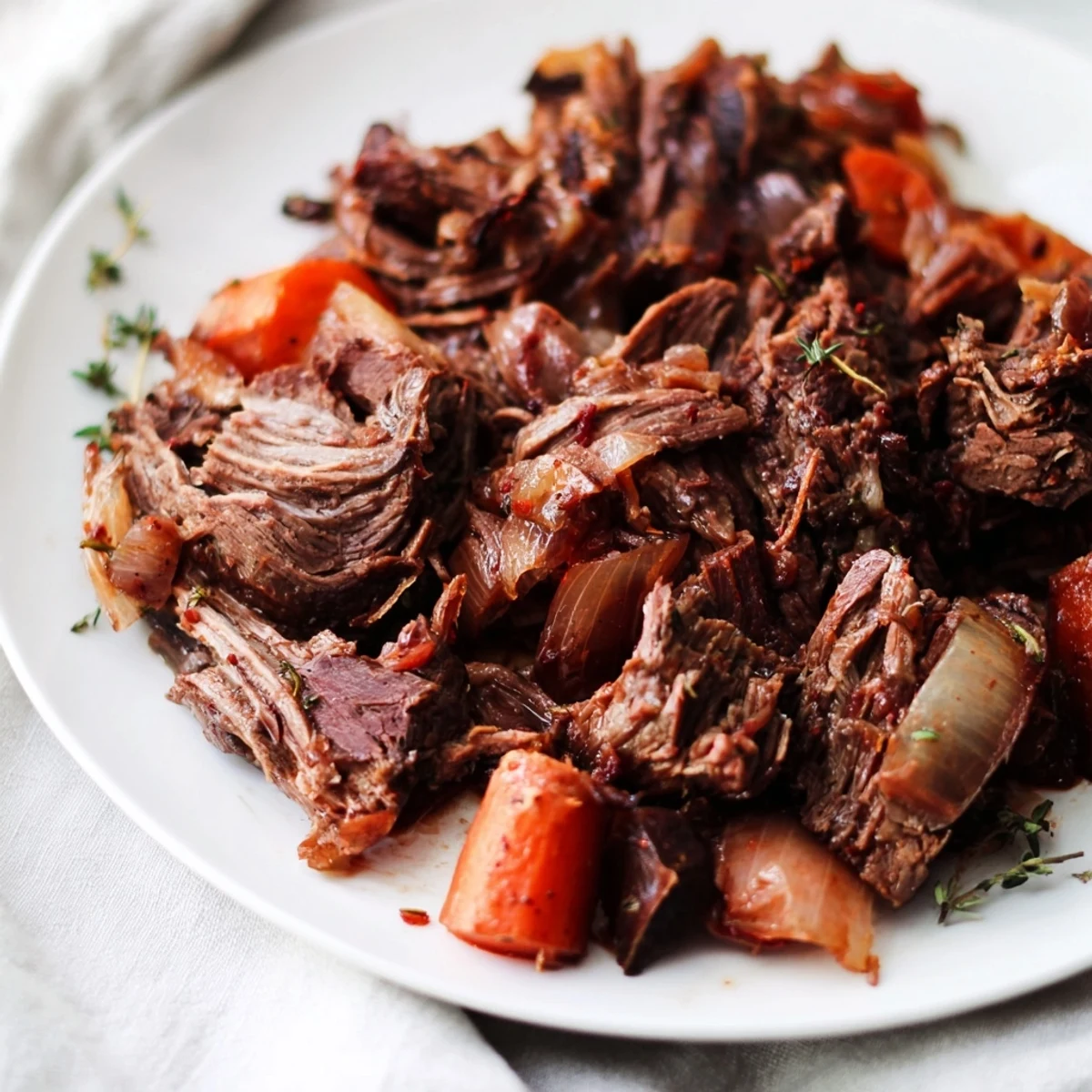 Tender herb braised beef chuck roast served with carrots and onions in rich gravy